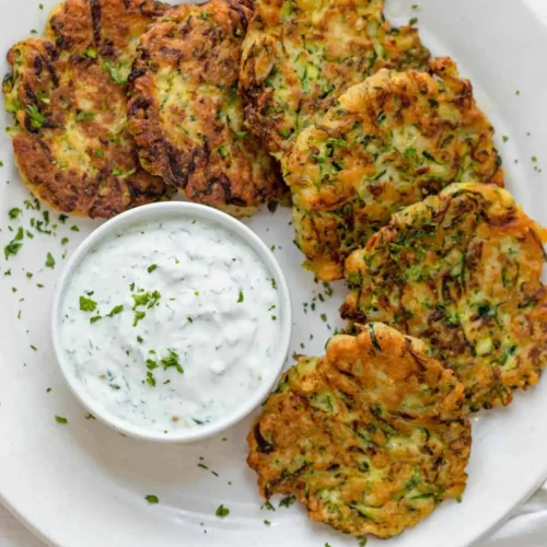 crispy zucchini fritters on a white plate