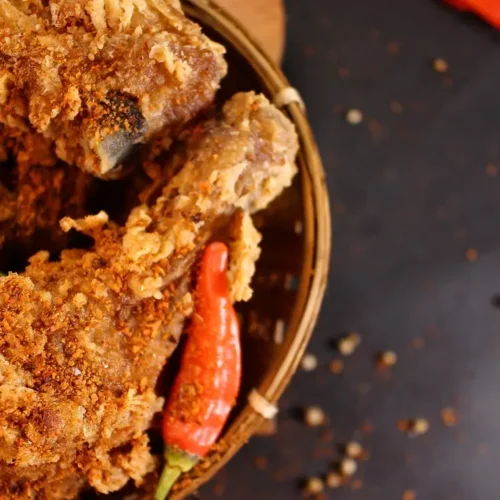 friend chicken drumstick in a bowl with hot peppers