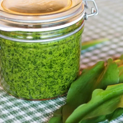 a glass jar full of bright green ramp pesto