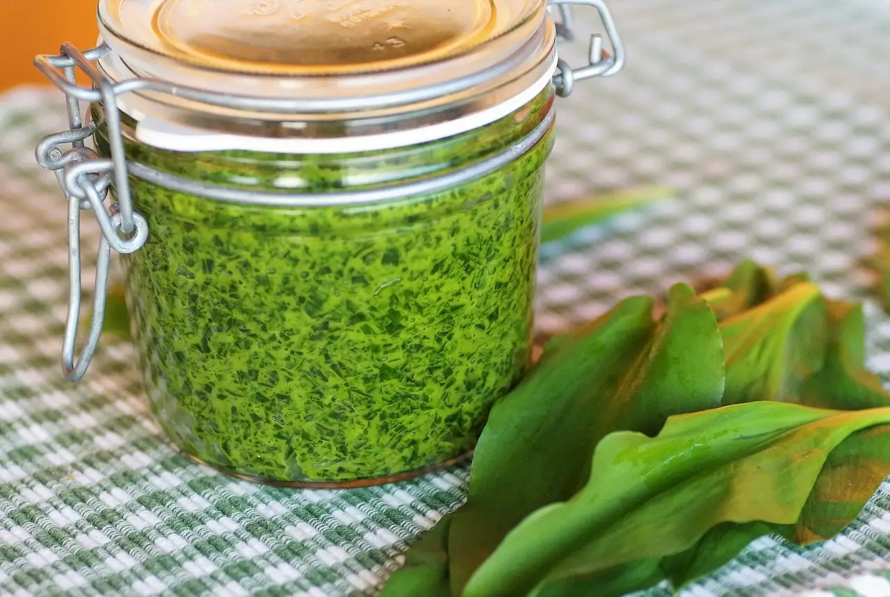 a glass jar full of bright green ramp pesto